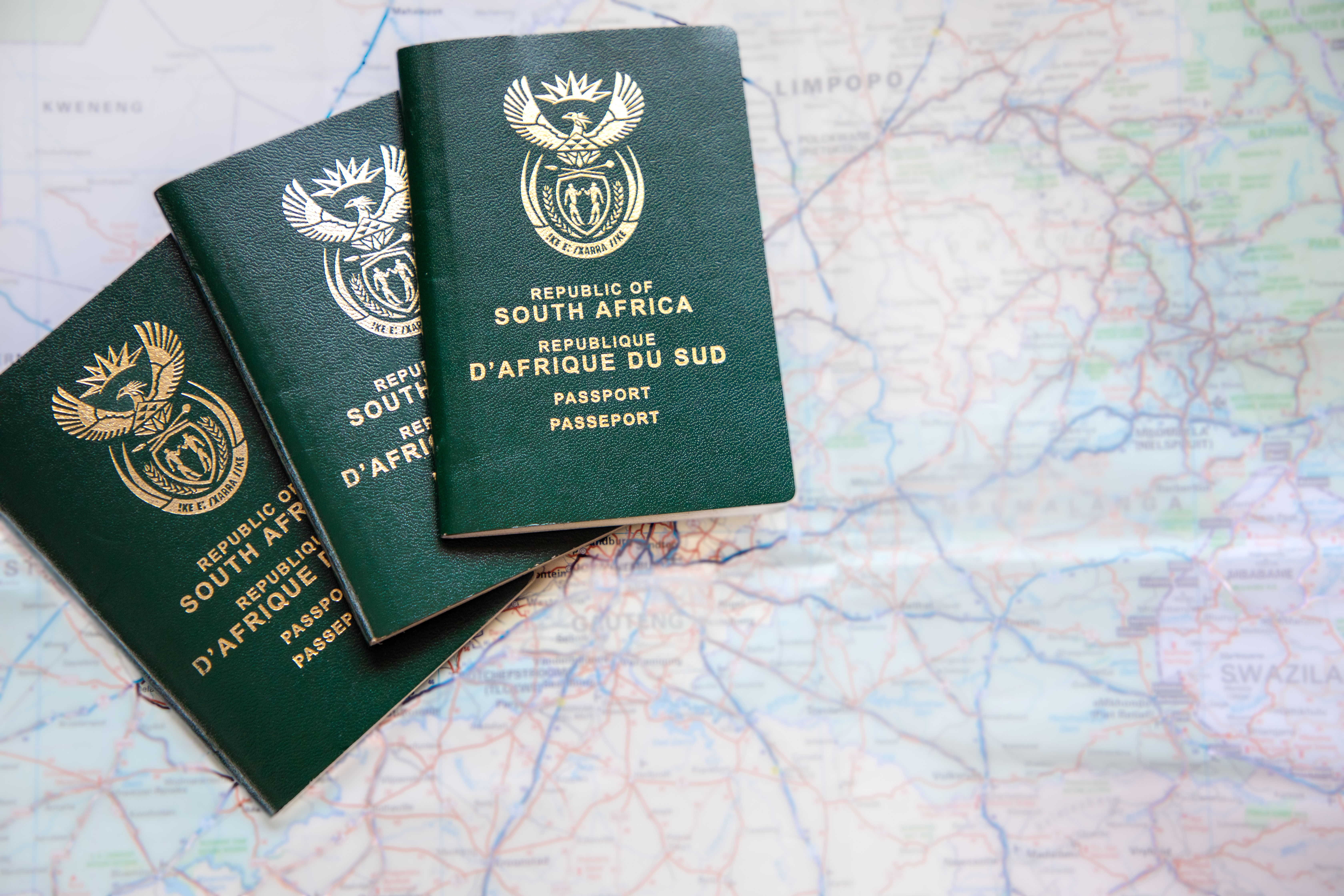 Three South African passports Three South African passports agains a out of focus map of South Africa. Concept for covid travel restrictions and travel ban
